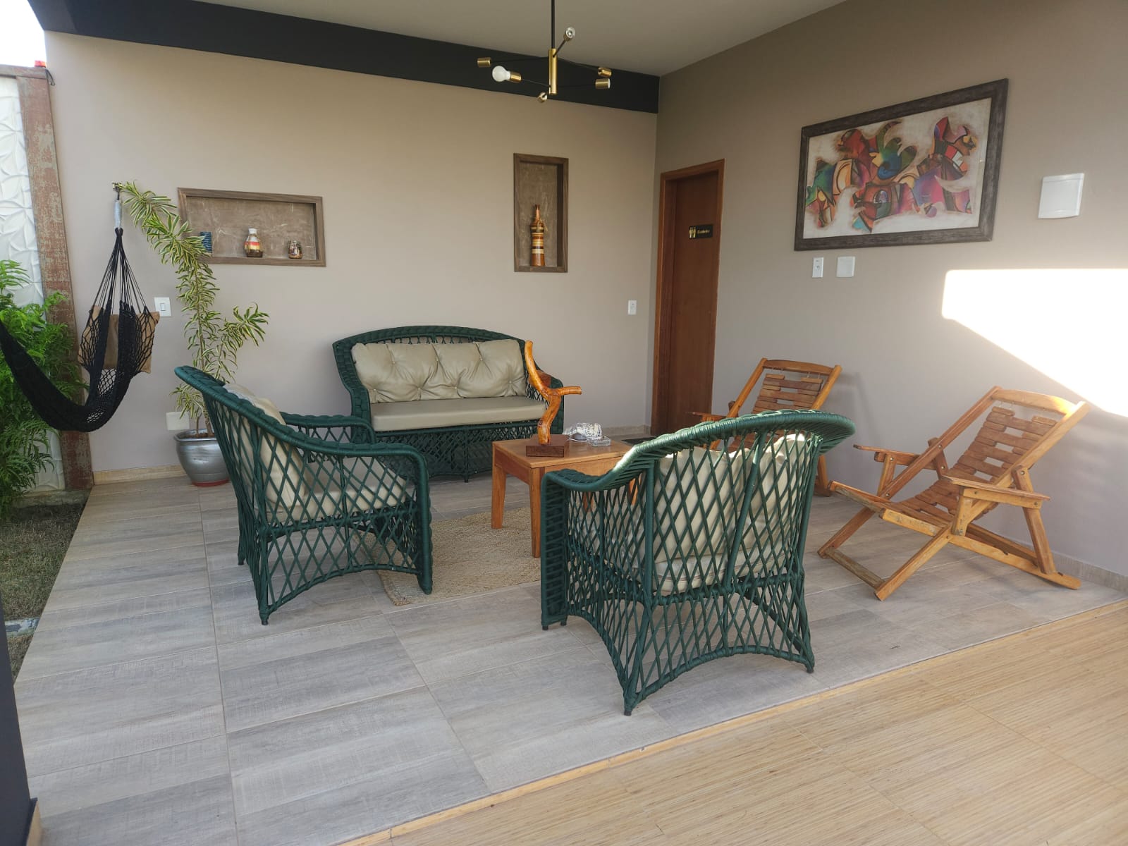 Lounge coberto com sofá, poltronas e rede